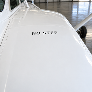 Aircraft stencil label reading "NO STEP" on white fuselage surface