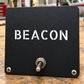 Black aircraft label plate with BEACON lettering and two mounting screws