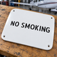 White metal aircraft warning label with NO SMOKING text and four corner screws