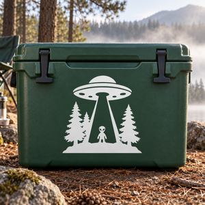 White alien and UFO vinyl decal with pine trees, shown on a dark green surface