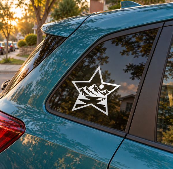 Mountain star vinyl decal on car window, white outline with black mountains and pine trees