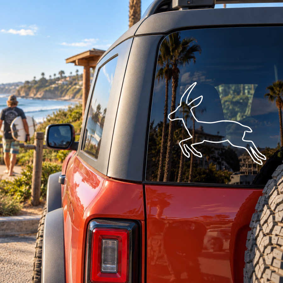 Outline antelope leaping vinyl decal on car rear window, white line art with tall horns.