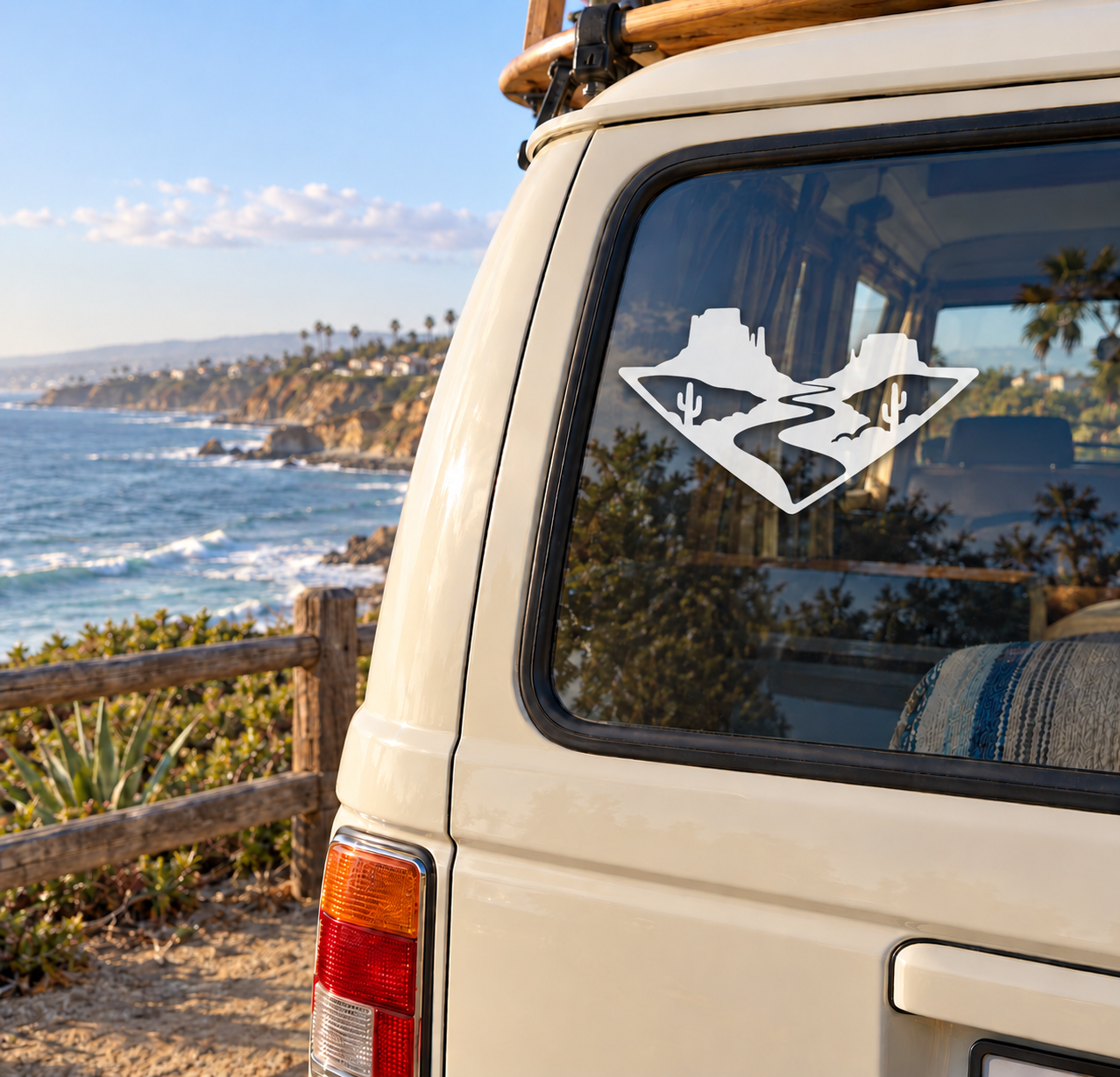 Arrowhead-shaped vinyl decal with desert canyon trail, cacti, and mountains on a van window