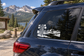 Black-and-white vinyl decal of tall pines, mountains, and lake on car window