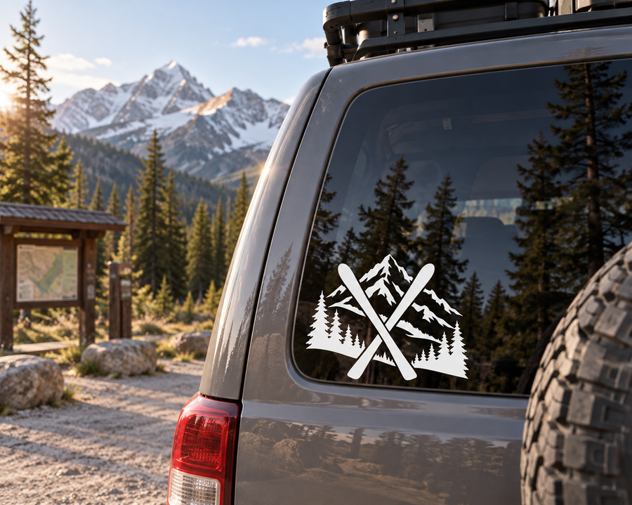 Vinyl decal of crossed skis over pine trees and mountains, black and white