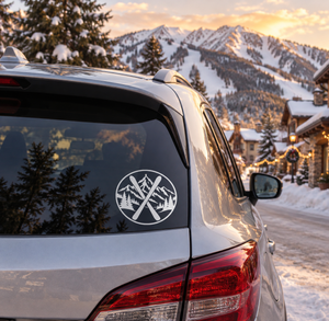 Circular vinyl decal with crossed skis and mountain pine scene on car window