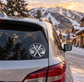 Circular vinyl decal with crossed skis and mountain pine scene on car window