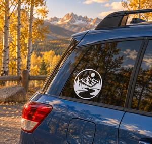 Circular vinyl decal with black-and-white mountain, pine trees, river, and sun