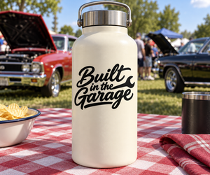 Cream insulated bottle with metal handle and “Built in the Garage” logo front.