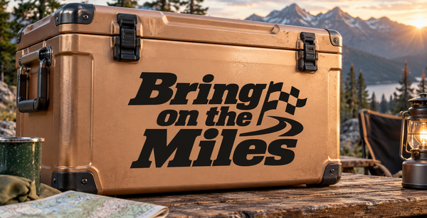 Tan hard cooler box with black handles and “Bring on the Miles” lettering