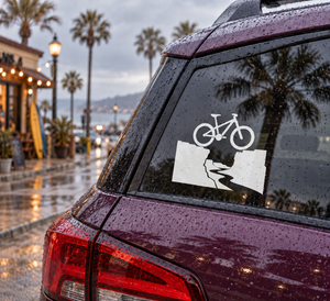 Vinyl bicycle route decal on car rear window, white bike icon over canyon silhouette