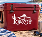 White bicycle vinyl decal with rider, cactus, and handlebar icons on a red surface
