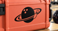 Vinyl decal featuring a black planet with orange dot craters and ring with small rocket icon