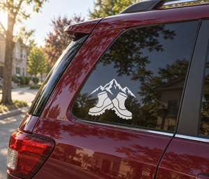 Vinyl decal of mountain peaks and hiking boots on a car window