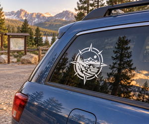 Vinyl compass decal showing mountain-and-fish emblem on car window