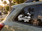 Skateboard vinyl decal with wave, palm trees, and sunset graphic on a car window