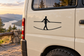 Black tightrope walker vinyl decal on a light vehicle panel