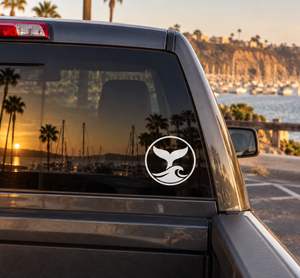 Whale tail vinyl decal with black logo in a white circle on car window