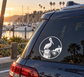 Round black-and-white vinyl decal with pelican crest on a car window