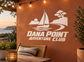 White vinyl decal with sailboat, waves, tree and “Dana Point Adventure Club” lettering.