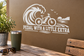 White vinyl e-bike pedal decal with roaring wave graphic and 'PEDAL WITH A LITTLE EXTRA'