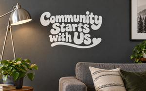White vinyl wall decal reading 'Community Starts with Us'