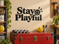 Black vinyl decal reading “Stay Playful” with smiling emoji face and sunburst rays