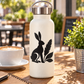 Black rabbit and feather vinyl decal on a light bottle