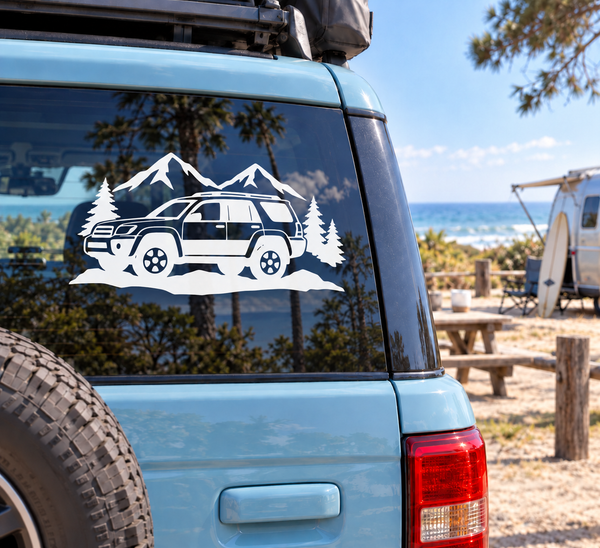 White vinyl decal of SUV with mountains and pine trees on vehicle side window
