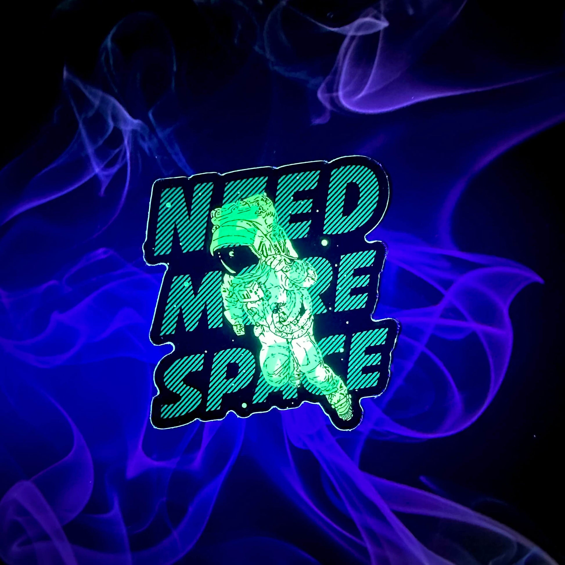 a glow in the dark vinyl sticker featuring text "Need More Space" with an illustrated floating astronaut