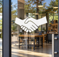 Handshake vinyl decal: white hands with black outline on window glass