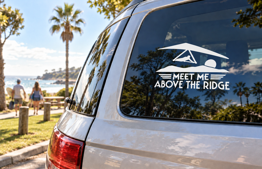 Vinyl hang-gliding window decal with 'MEET ME ABOVE THE RIDGE' on car glass