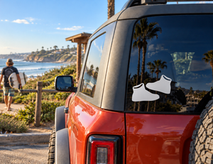 Street sneaker vinyl decal pair on car window: two black shoes with white outlines