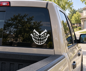 Grinning monster vinyl decal on car window, white and black cartoon face
