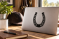 Black horseshoe vinyl decal with dotted trim on a laptop surface