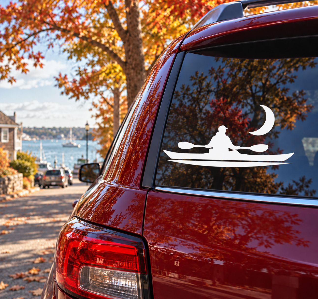 Black kayak paddler and moon vinyl decal on red vehicle rear window