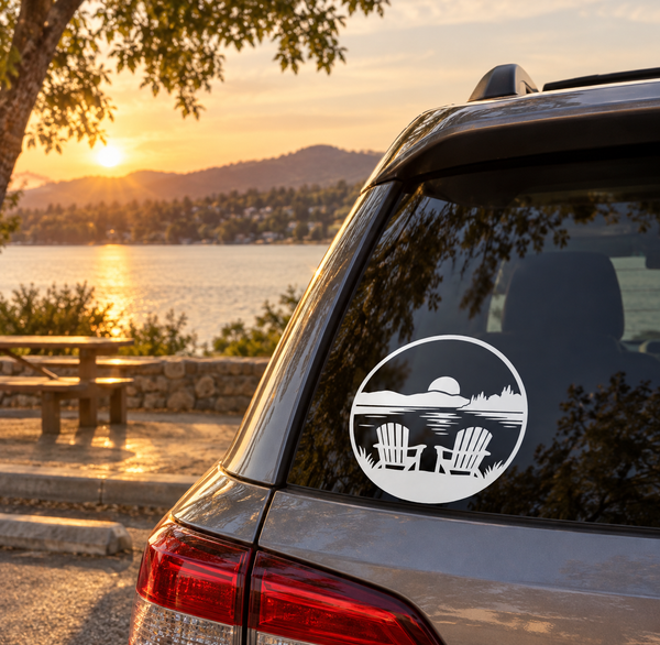 Round vinyl decal showing lake view with two chairs and mountain silhouette on car window