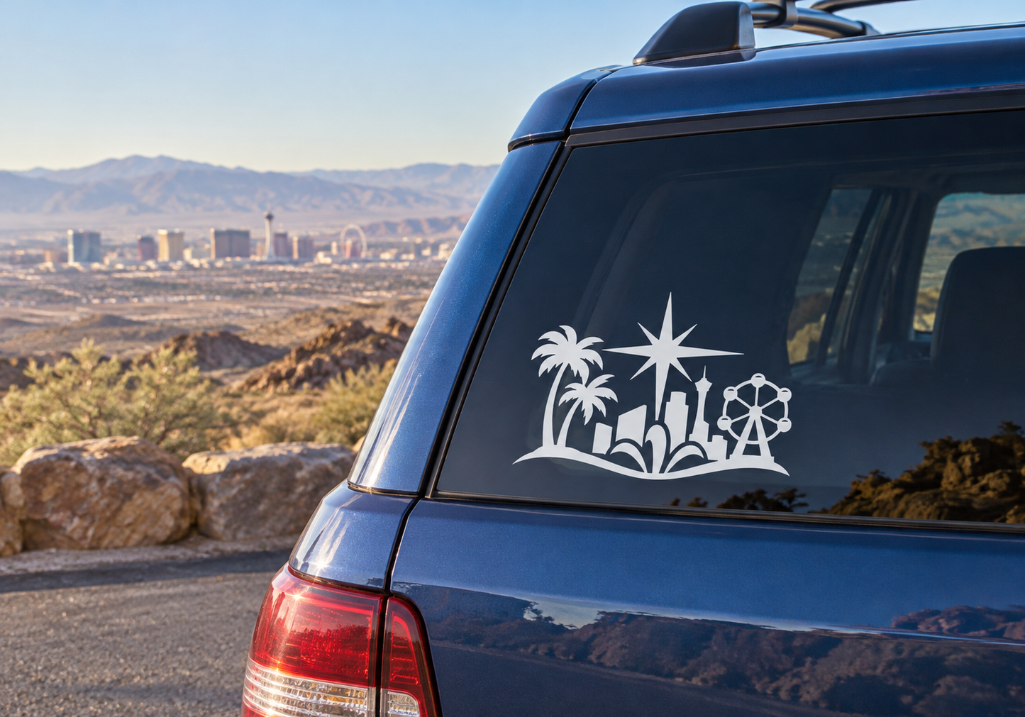Black vinyl decal of desert skyline with palm trees, starburst, and atomic-style wheel on car glass