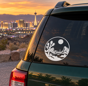 Round white vinyl decal with desert skyline, cactus, and moon on car window