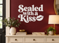 Sealed with a Kiss vinyl decal with white lettering and kiss lip graphic on dark red wall