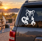 Vinyl decal of seated cartoon mascot animal with paws on belly on dark car window.