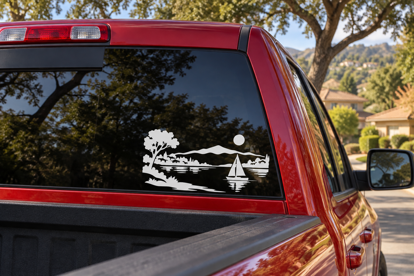 Black vinyl sailboat horizon decal on car rear window with trees, lake, and small sailboat