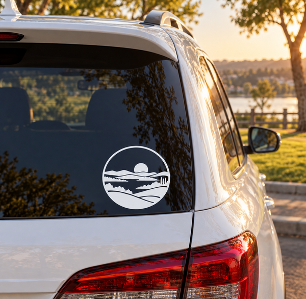 Circular vinyl decal with Mission Viejo landscape crest, white on dark blue, on car window