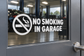 No smoking in garage vinyl decal with crossed cigarette icon and bold text on glass
