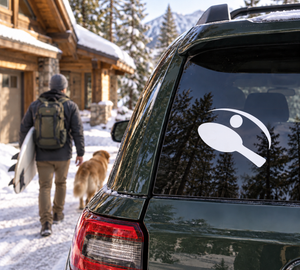 White ping pong paddle and ball vinyl decal on dark car window glass