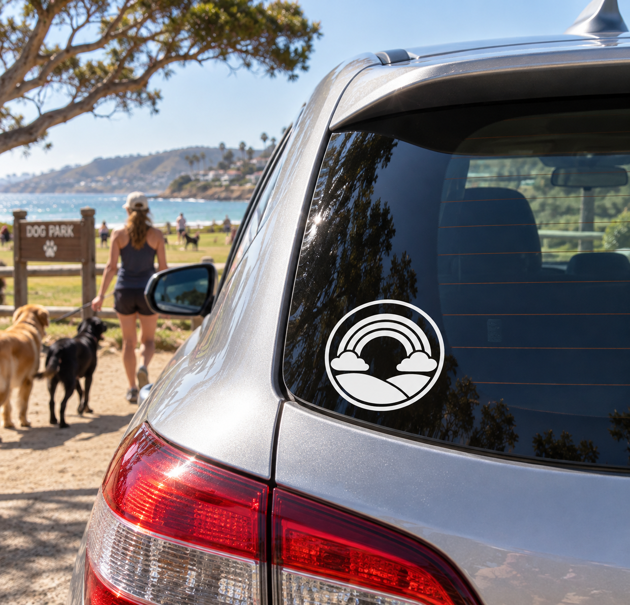 Round vinyl car decal with rainbow arches over mountain and cloud silhouettes