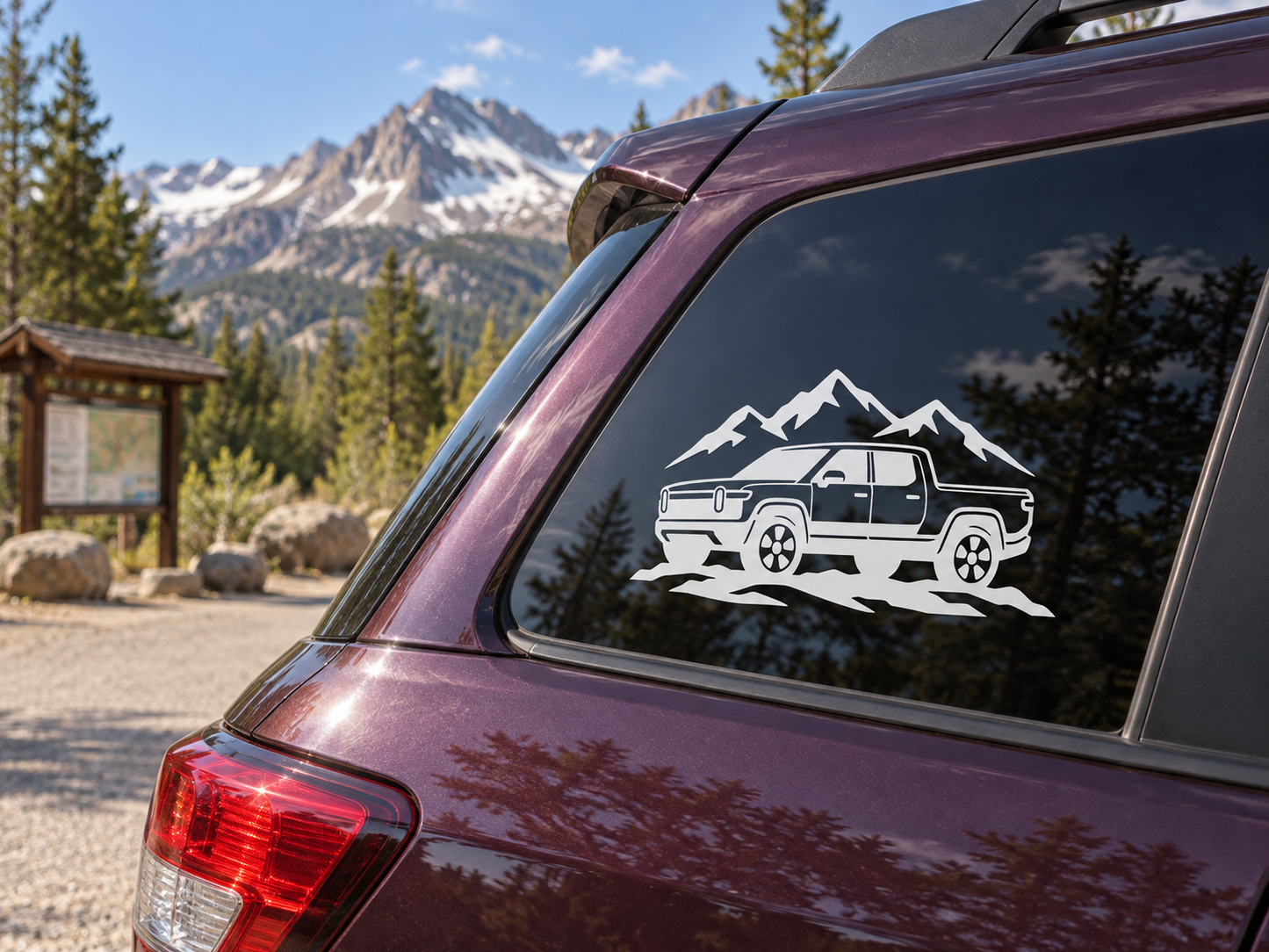 White mountain-and-truck vinyl decal on a car rear side window