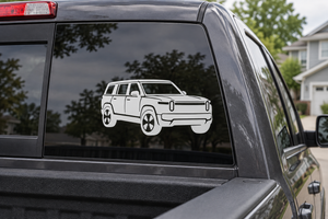 Rivian R1S front three-quarter vinyl decal, white car graphic on dark window glass.