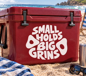 Vinyl decal reading “SMALL HOLDS BIG GRINS” in white letters on red surface