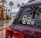 Three white nesting doll vinyl decals with flower designs on a car window